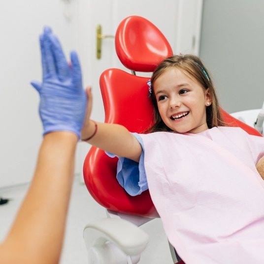 Smiling child giving dentist a high five