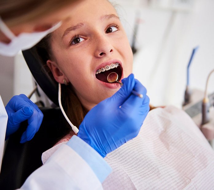 A dentist examining a child with braces