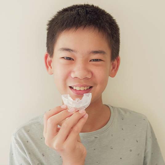 Preteen boy holding a custom athletic mouthguard
