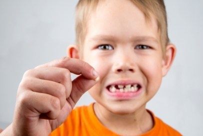 Upset child holding a knocked out permanent tooth