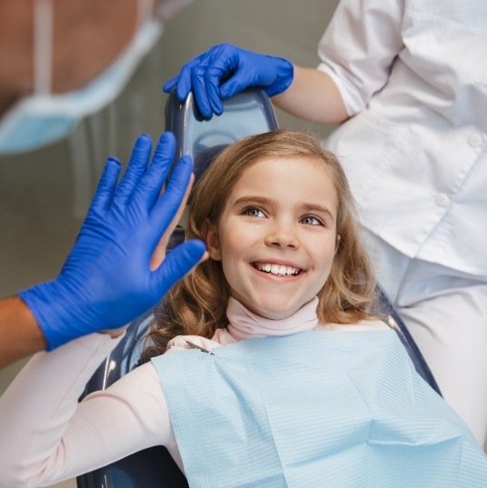 Child giving dentist a high five during treatment to prevent dental emergencies