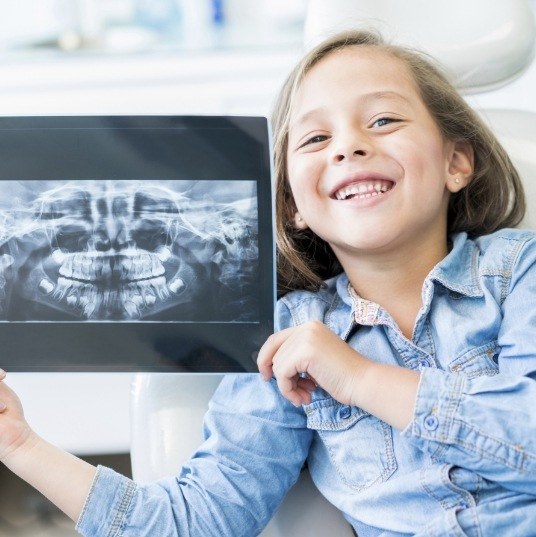 Smiling child holding up digital x-ray images