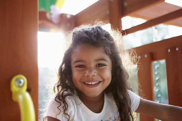 little girl smiling on playgym outdoors 