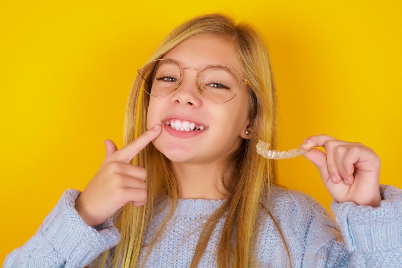 A young girl showing off her clear aligner