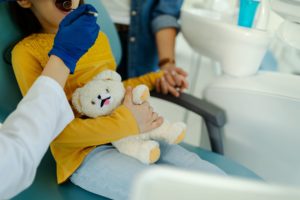 Girl with teddy bear in dentist's chair